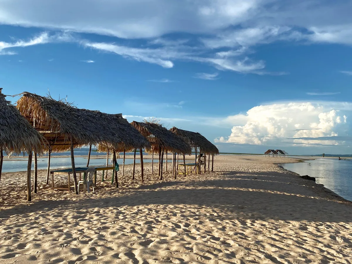 Praia de areia branca com quiosques de palha às margens do rio Tapajós, em Alter do Chão